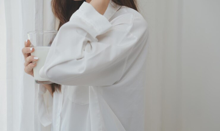 Photo 自宅の寝室のベッドでラップトップを使用しながら、笑顔でカメラを見ているカジュアルな服を着た幸せな若い女性