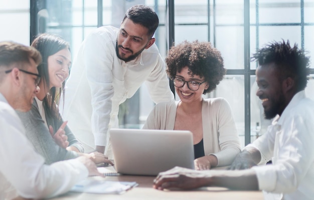 Happy young female employee discussing online project showing computer presentation to skilled team leader in eyeglasses Friendly diverse colleagues working in pairs on laptop using applications