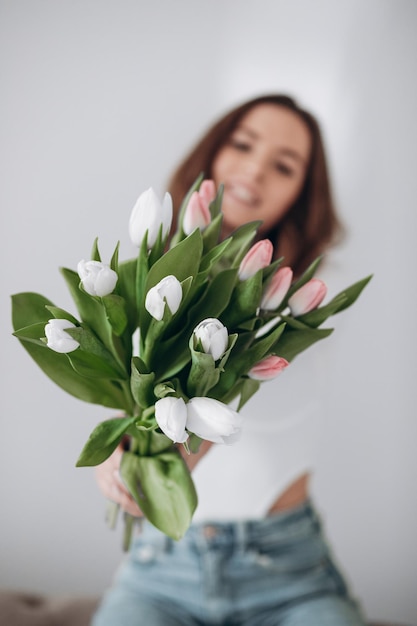 Happy young female smiling and holding bouquet of tulips while celebrating Women Day
