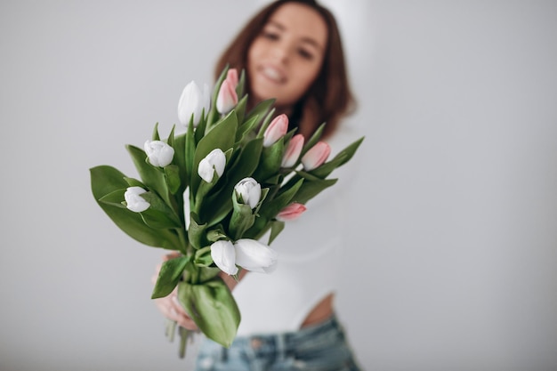 Happy young female smiling and holding bouquet of tulips while celebrating Women Day