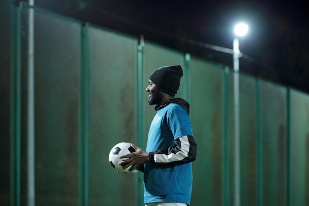 Foto felice giovane calciatore con allenamento con pallone da calcio allo stadio