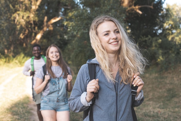 Счастливые молодые друзья гуляют по летнему лесу