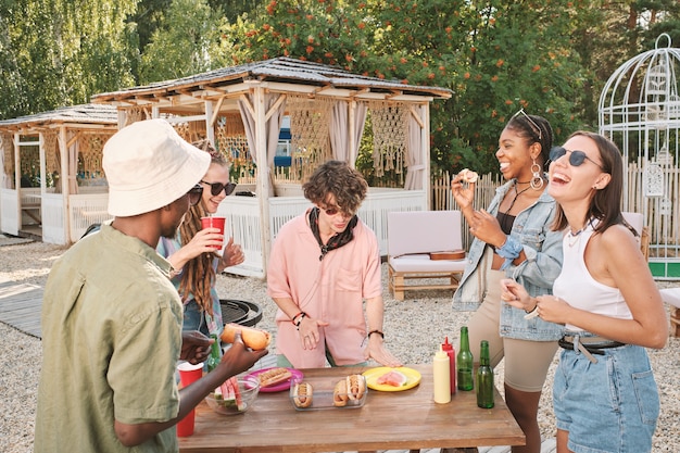 Happy young friends having fun by table with snacks