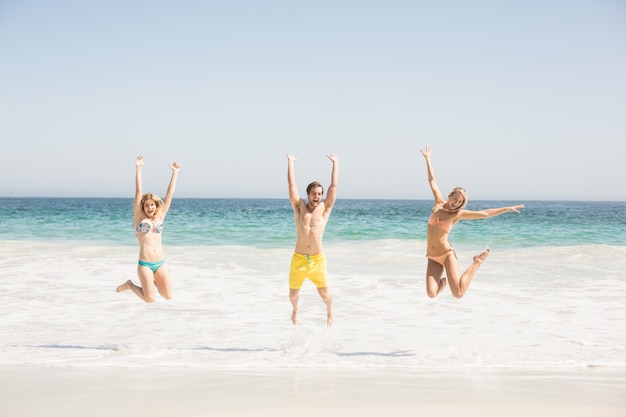 Happy young friends jumping on the beach