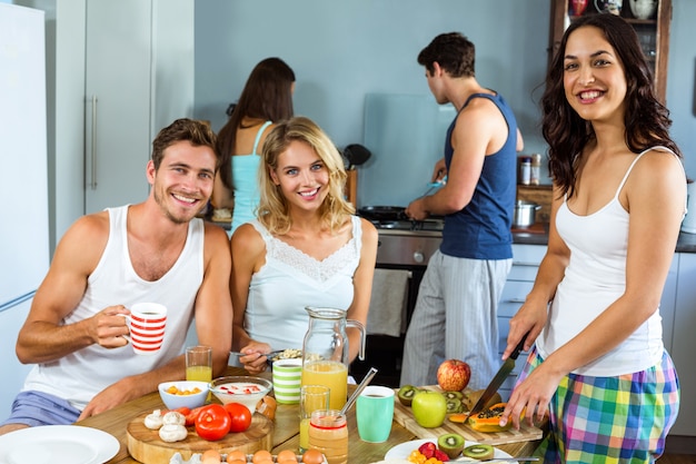 Happy young friends preparing breakfast in kitchen