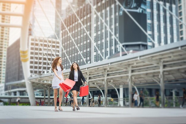 写真 ショッピングバッグを持った幸せな若い友達が街の歩道を歩いています