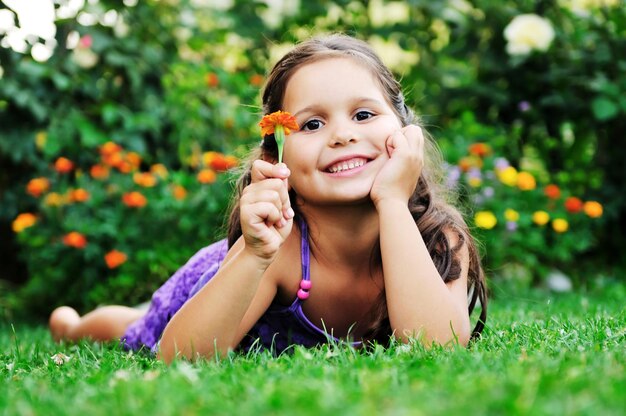 幸せな若い女の子の子供たちは嘘をリラックスし、花と草の上で楽しんでください