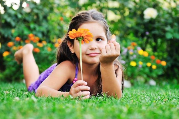 행복한 어린 소녀 아이들은 거짓말을 쉬고 꽃과 함께 잔디에서 즐거운 시간을 보낸다
