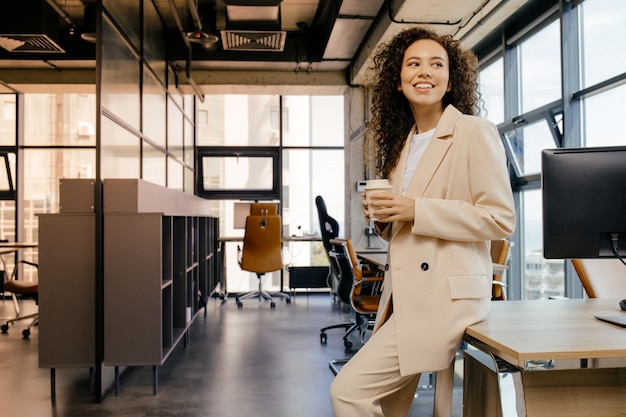 Happy young girl drinking coffee on lunch break in office