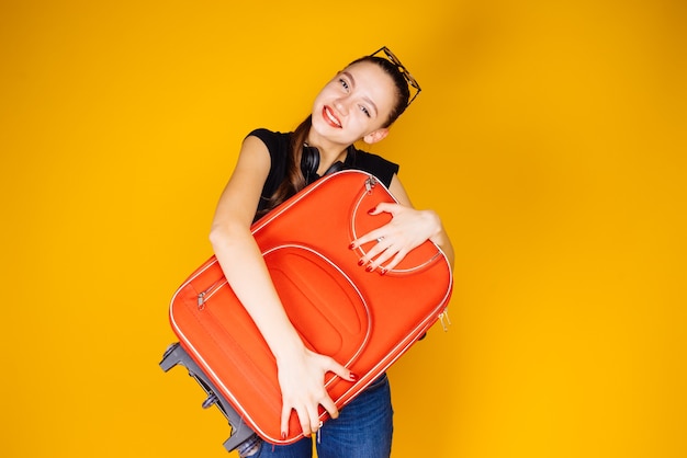 Happy young girl going on vacation, adventure, holding a big red suitcase