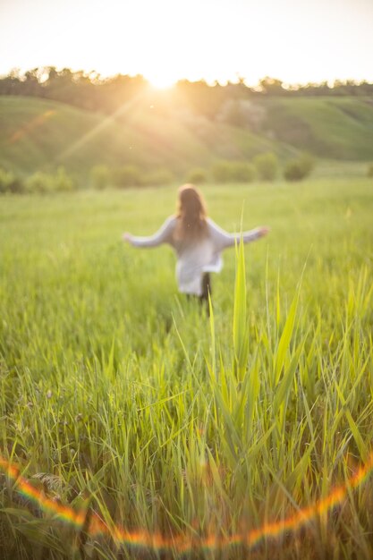 HAPPY YOUNG GIRL ON A GREEN MEADOW SELECTIVE FOCUS ON THE GRASS GRASS IN FOREGO GIRL IS BLURRED