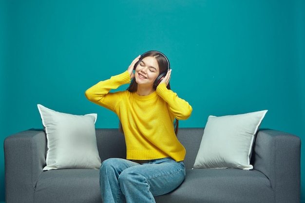 Happy young girl in headphones listen to modern music playlist enjoying sound closed eyes sitting on