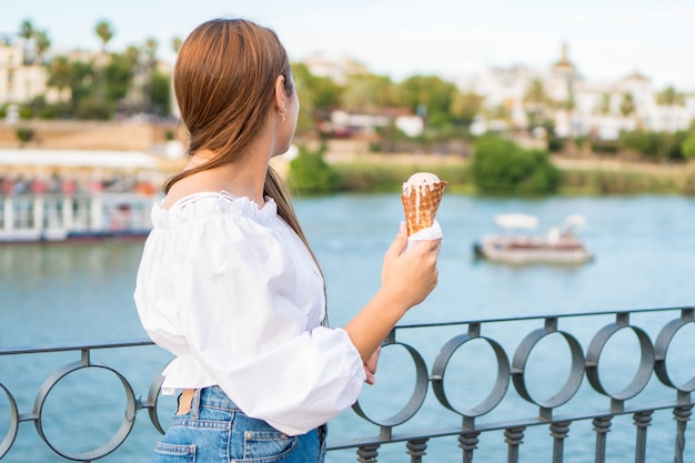 Happy young girl on her back eating an ice cream in summer in Spain enjoying the view of the river