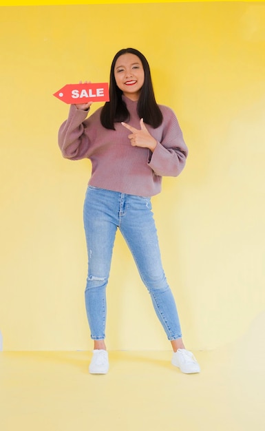 Happy young girl hold red paper , Asian girl wear brow sweater on yellow background.