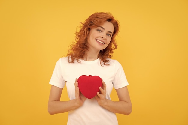 Ragazza felice che tiene il cuore di san valentino su sfondo giallo 14 febbraio