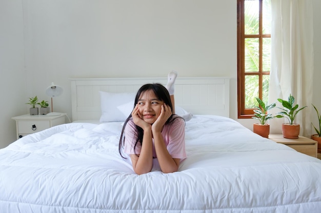 Happy young girl laying on bedroom at house