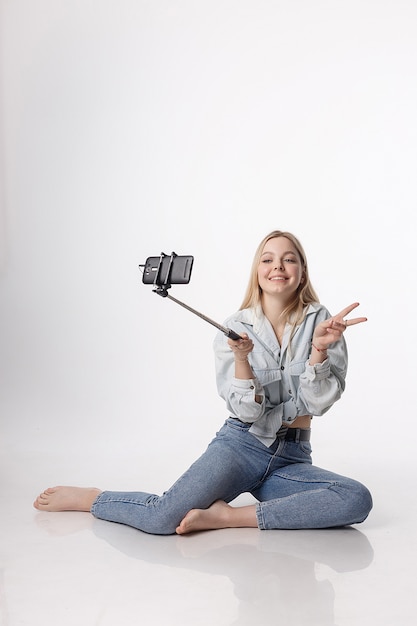 happy young girl making self portrait with smartphone attached to selfie stick