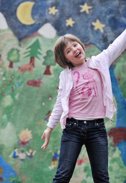 happy young girl posing and jumping with abstract urban style painting bacground begind