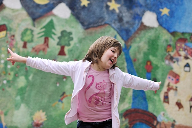 happy young girl posing and jumping with abstract urban style painting bacground begind