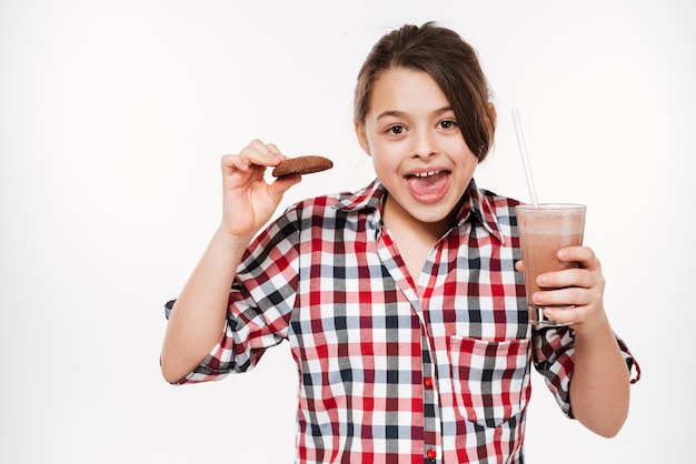 Foto ragazza felice che posa con il biscotto e il cacao