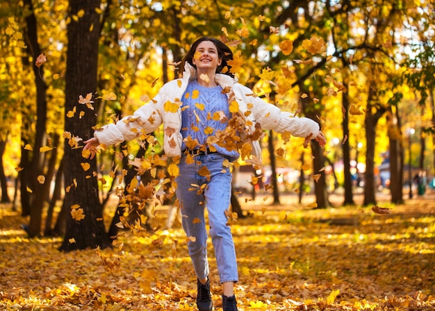 秋の公園で走っている幸せな若い女の子