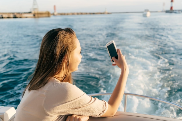 Happy young girl sailing on a yacht on the Caribbean sea enjoying vacation and photographing the landscape