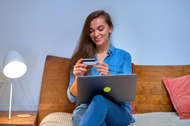 Photo happy young girl shopper shopaholic shopping online and paying for goods and purchases using credit card and laptop. e-commerce and modern lifestyle