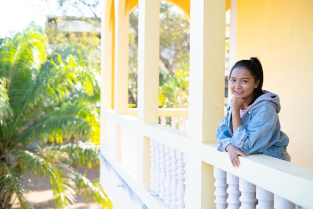 Happy young girl standing at building yellow background