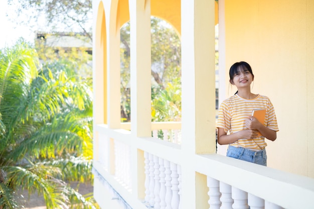 Happy young girl standing at building yellow background