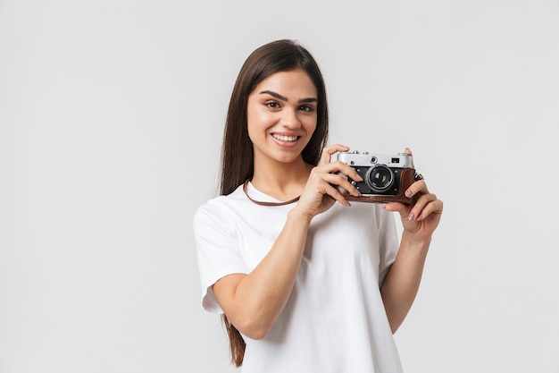 Happy young girl standing isolated on white, holding photo camera