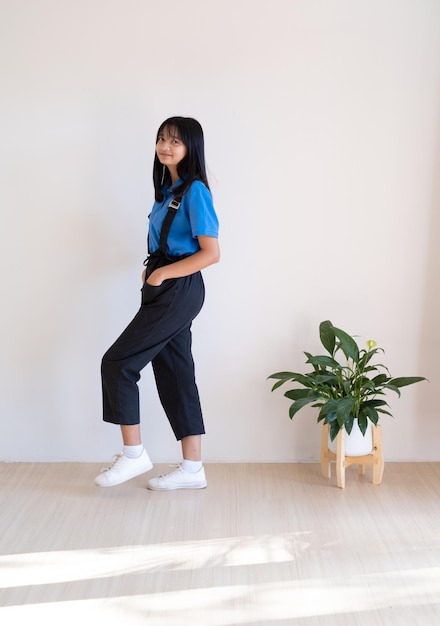 Happy young girl standing on the wood floor with green plant in minimal room