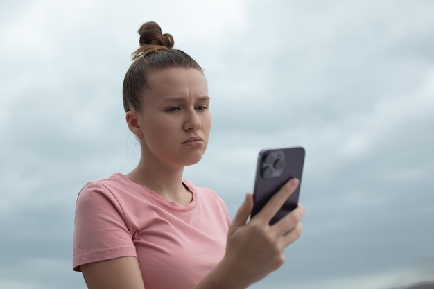 Happy young girl uses her phone on the roof of a house balcony city background a woman taking selfie