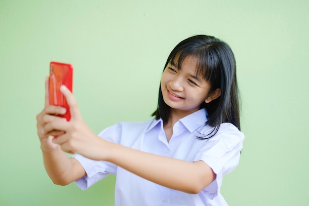 Happy young girl using smartphone on green background,Asian girl,School girl.