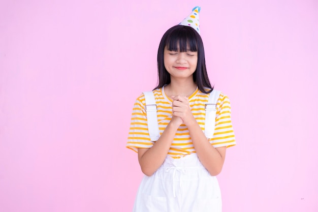 Happy young girl wear party hat on pink background,Asian girl.