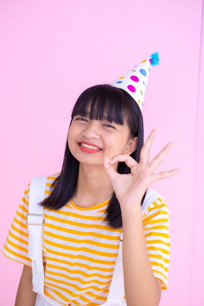 Happy young girl wear party hat on pink background,Asian girl.