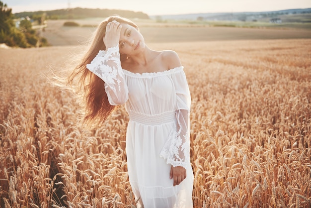 Happy young girl in a wheat field under sunlight.