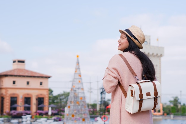 美しい街を楽しむバックパックを持つ幸せな若い女の子美しい街の背景にスマートフォンを持つ観光旅行者