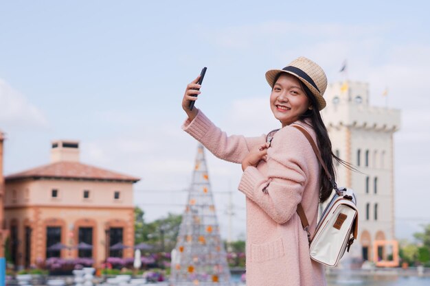 Photo happy young girl with backpack enjoying at beautiful city tourist traveler with smartphone on background beautiful city