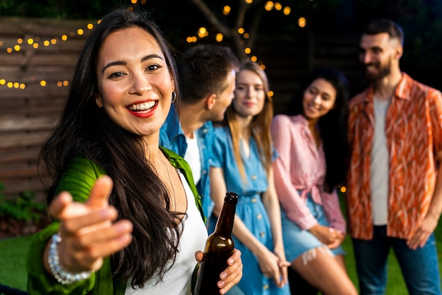 Foto ragazza felice con birra che esamina macchina fotografica