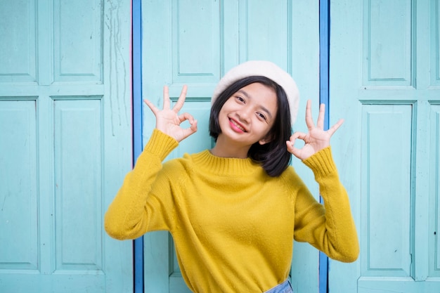 青いドアの背景を持つ幸せな少女