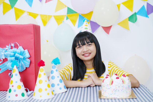 写真 白い背景の上の誕生日パーティーのケーキと幸せな少女。