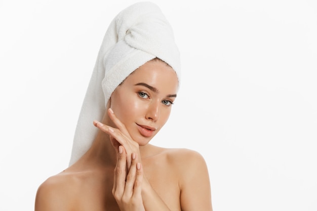 Happy young girl with clean skin and with a white towel on her head washes face.