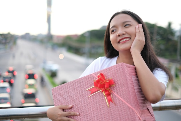 Счастливая молодая девушка с подарочной коробкой