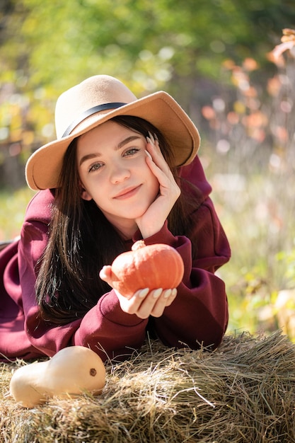 Happy young girl with pumpkin in autumn garden