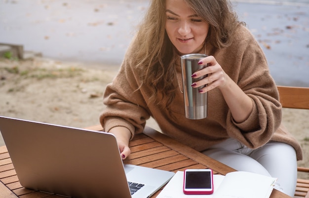 Photo happy young girl working at a coffee shop with a laptop