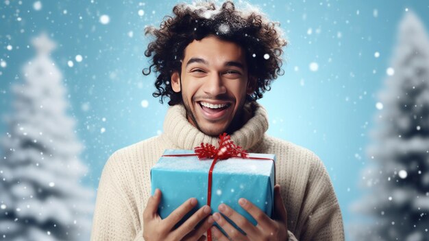 Happy young guy or man with a box of Christmas present on a blue snowy background Vivid emotions Ne