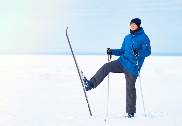 Счастливый молодой парень катается на лыжах зимой. Человек на беговых лыжах, зимние развлечения. Копировать пространство