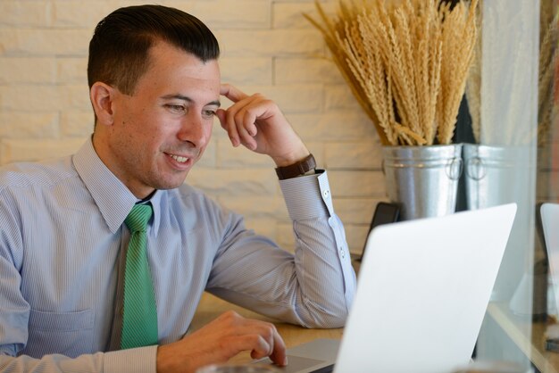 Happy young handsome businessman using laptop at the coffee shop