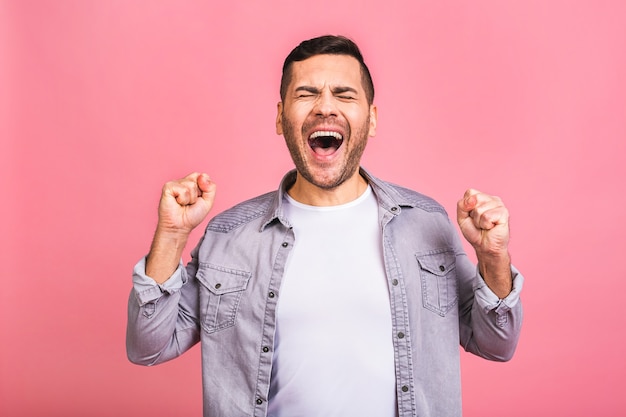 ジェスチャーと口を開いたままの勝利を祝う幸せな若いハンサムな男