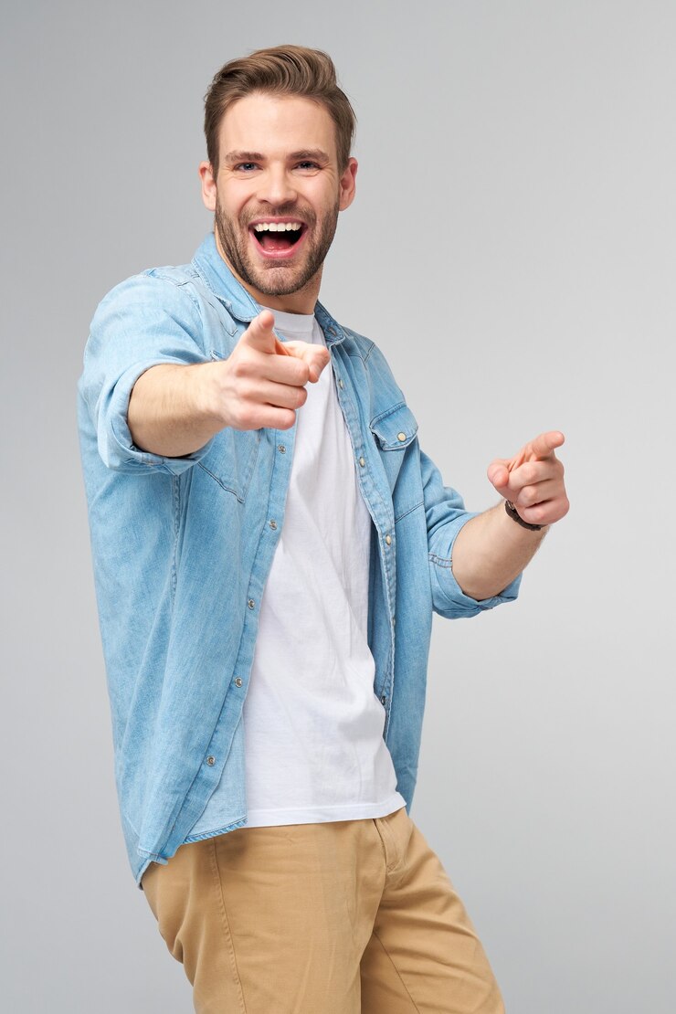 Photo happy young handsome man in jeans shirt pointing on camera standing  